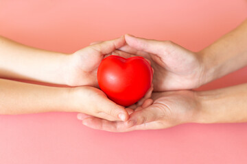 Adult and child hands holding red heart, health care love, give, hope and family concept, world...