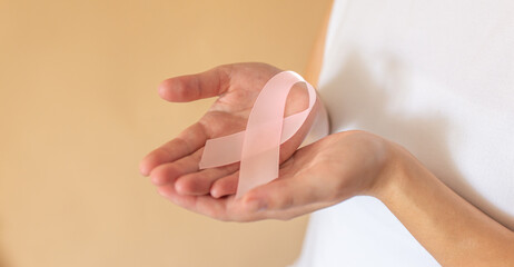 Close up of woman showing pink ribbon symbolizing breast cancer