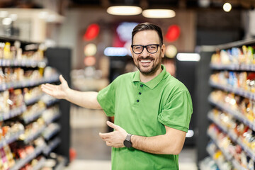 Friendly employee welcoming customers in supermarket.