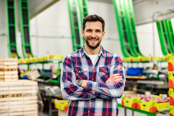 A proud food factory worker standing in storage and smiling at the camera.