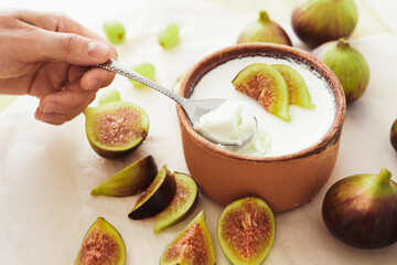 Spoon and delicious natural Greek yogurt in clay bowl with figs