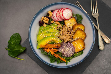 Top view of a buddha bowl, vegan salad of baked vegetables, avocado, tofu, and quinoa with rice