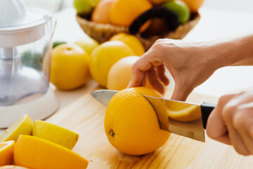 Female hands with knife cutting orange fruit for homemade fresh juice - Powered by Adobe