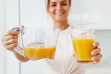 Young cheerful woman with  big glass of fresh orange juice