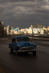 Old car on Malecon street of Havana with storm clouds in background. Cuba