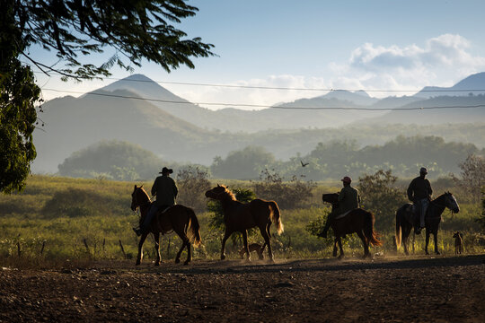 Silhouette of country man on horses with beautiful mountains in background in Vinales, Cuba