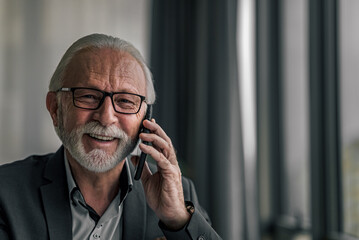 Portrait of senior business professional talking on mobile phone at corporate office