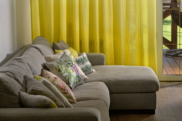 sofa pillows on a gray sofa, yellow textiles, yellow curtains in the interior
