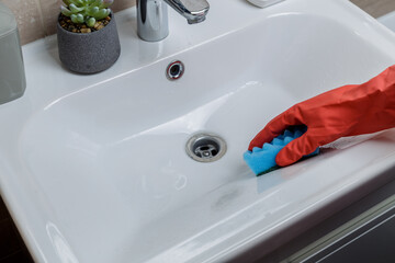 Hand of woman in protective gloves cleaning tile using microfiber cloth and detergent, concept of...