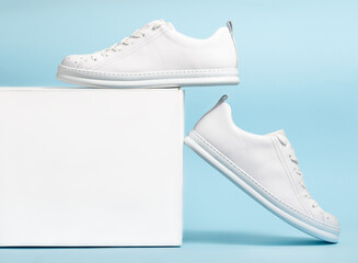 Pair of Stylis New White Sneakers and white box Over light blue Background. Horizontal Image
