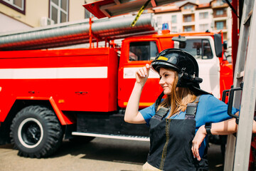 Female firefighter in protective uniform standing near red fire truck