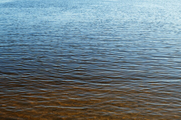 Water waves background. River surface near the shore