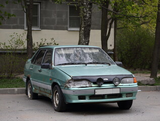 Fototapeta premium Old Soviet car with a broken headlight, Dybenko Street, St. Petersburg, Russia, May 2022