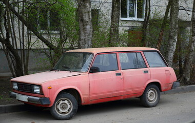 Old Soviet faded pink car, Dybenko Street, St. Petersburg, Russia, May 2022