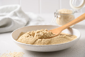 Sesame flour in white bowl on white kitchen background. Close up.