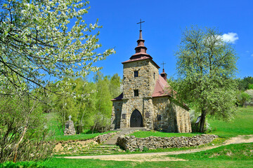 A  stone church in the picturesque landscape in Huta Polanska of the Low Beskids (Beskid Niski) in spring sunny day, Poland