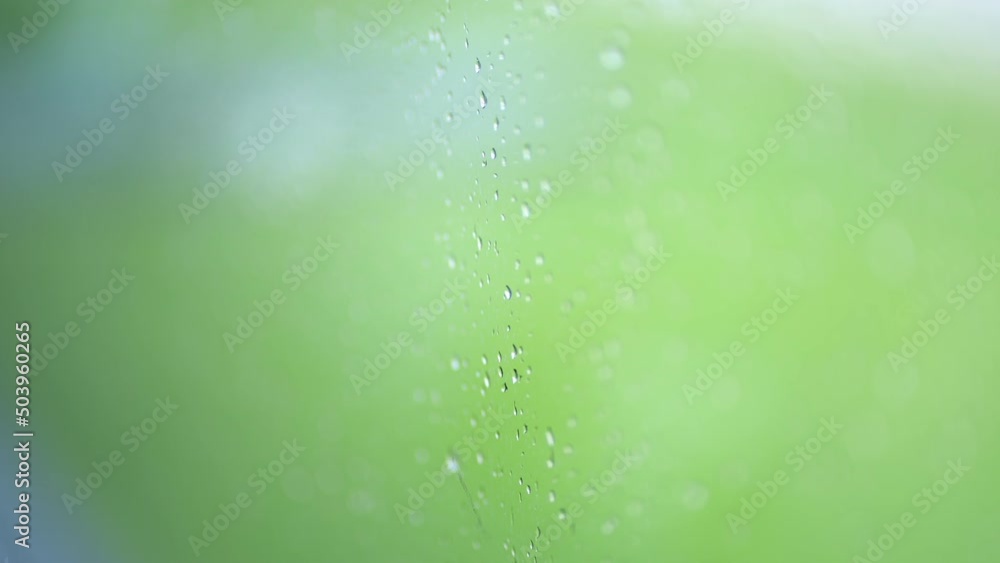 Poster racking focus on rain droplets on a window with an out of focus background.