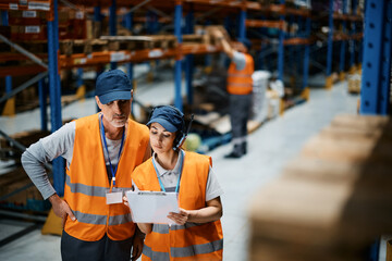 Warehouse manager and her mature coworker analyzing shipment plans while working at distribution warehouse.