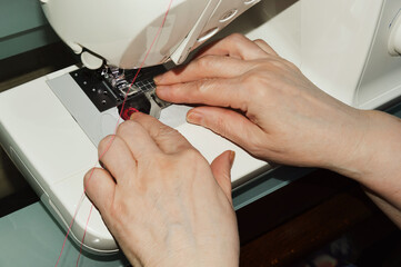 Obraz na płótnie Canvas a woman sews on a sewing machine. hands thread the thread.