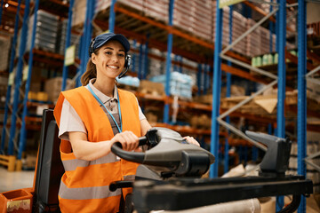 Fototapeta na wymiar Happy female worker driving pallet jack while working at distribution warehouse.