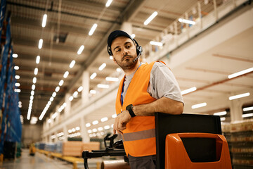Fototapeta premium Warehouse worker driving pallet jack at storage compartment.