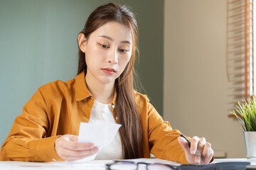 Asian young employee, business woman calculate tax income and expenses, bills, credit card for...