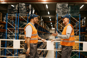 Happy mature worker talks to warehouse dispatcher at storage compartment.