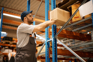 Young male worker works with packages at distribution warehouse.
