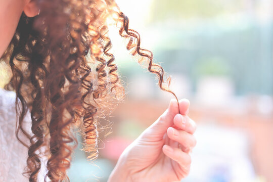 Close-Up of a woman playing with her corkscrew curled hair