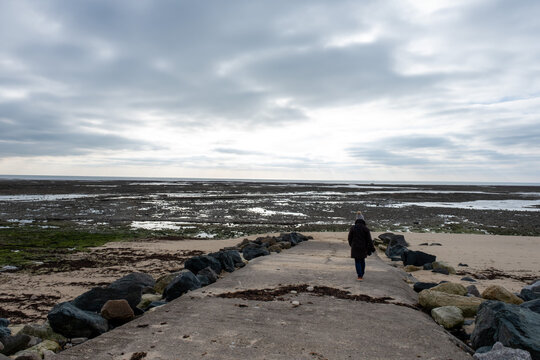 Rear view of a woman standing on beach looking out to see in winter, Ile de Re, Rivedoux et Ars en Re, Charente Maritime, France