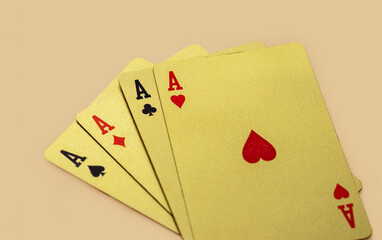 golden casino playing cards in a row or chaotic arrangement on orange background. four aces isolated, joker card on the top. Gold plated poker playing cards. luxury,waterproof