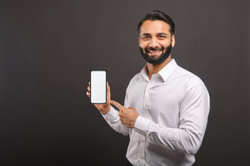 Mock-up concept. Handsome confident bearded Indian man in formal wear showing smartphone with empty...