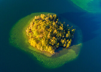 Top view of a small green island in the blue lake