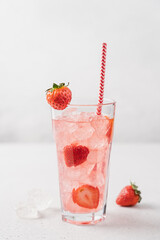 Strawberry lemonade with ice in tall glass on light gray background. Berry refreshing summer drink with straw