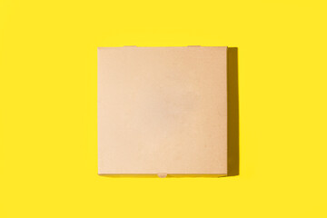 Caja de cartón para pizza en blanco sobre un fondo amarillo liso y aislado. Vista superior y de cerca. Copy space