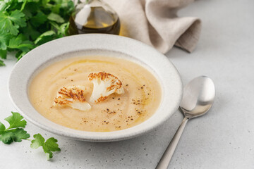 Cauliflower soup in bowl on light background. Vegetable Vegan cream soup with parsley