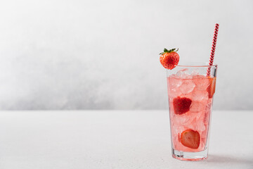 Strawberry lemonade with ice in tall glass on light gray background. Berry refreshing summer drink...