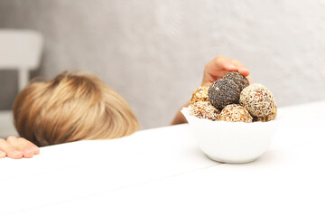 Child hands stealthily taking energy balls in the kitchen.