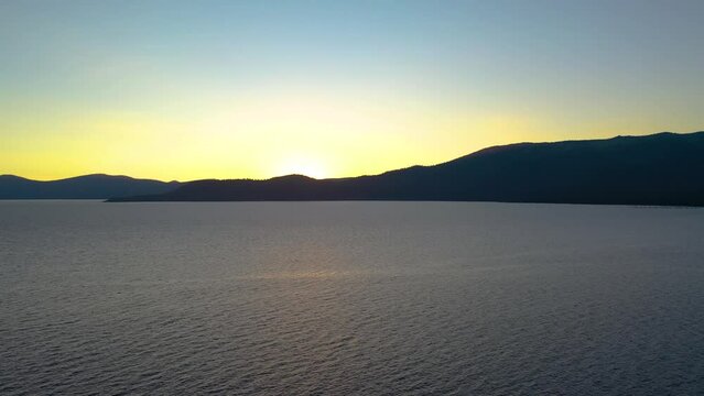 Yellow Sun Setting Behind Beautiful Lake Tahoe in the Seara Nevado Mountains California, Alpenglow on Pristine Mountain Peak - Aerial Drone View