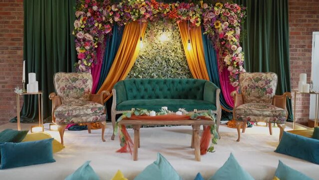 A beautiful and colorful wedding stage setup called mehndi vanue in a hall.