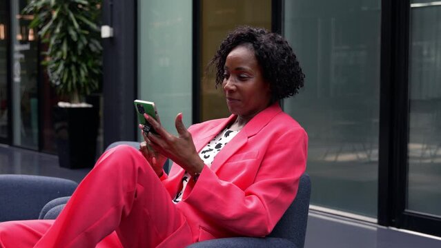 Smiling businesswoman using smart phone in office / London, UK
