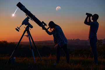 Couple stargazing together with a astronomical telescope, looking at planets, stars, lunar eclipse...