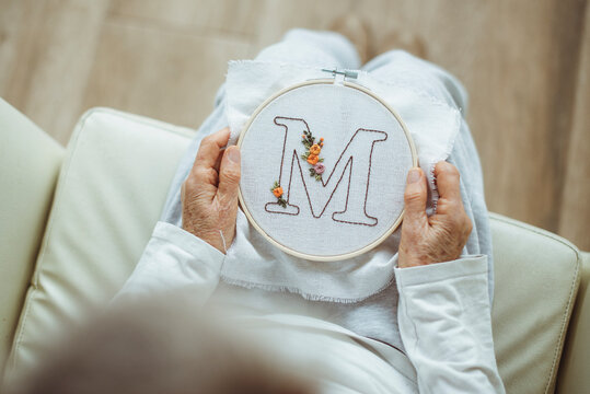 Overhead view of a woman holding an embroidery hoop with the letter M