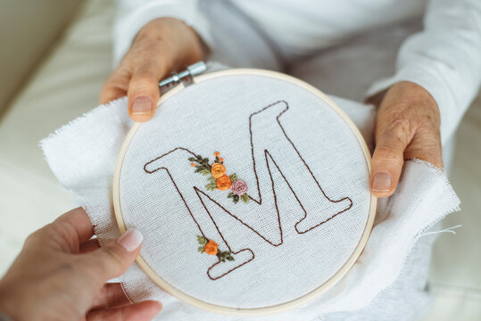 Woman giving an embroidery hoop with the letter M to her senior mother