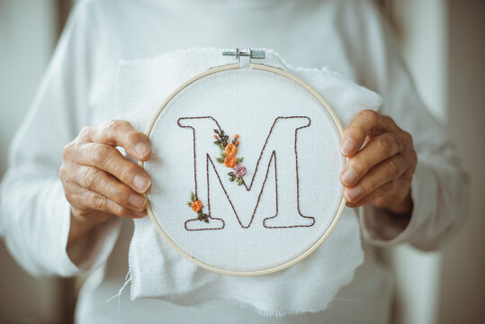 Senior woman holding an embroidery hoop with the letter M