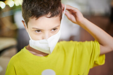 Ten years old kid wearing a colorist shirt  adjusts a protective face mask. Summertime concept.
