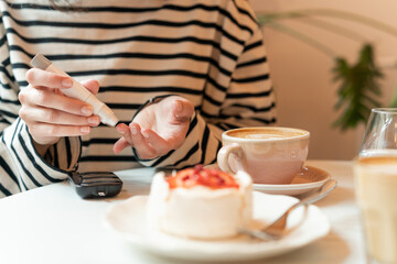 Diabetic woman sitting at a table testing blood sugar level in a cafe before eating