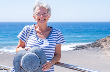 Fototapeta na wymiar Happiness and good mood in senior smiling woman in outdoors sea excursion. Attractive white haired lady dressed in blue expressing freedom and joy. Horizon over water