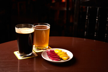 Pickled Marinated eggs pink and yellow on a white plate and glass of beer in pub