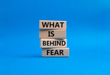 What is behind fear symbol. Concept words what is behind fear on wooden blocks. Beautiful blue background. Business and what is behind fear concept. Copy space.